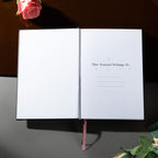 Open Dream Garden notebook showing the "This Journal Belongs To" ownership page with delicate star and circle details, styled with pink roses on a dark surface.