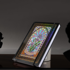 Black and purple holographic iris Dream Garden cardboard notebook resting angled on a dark reflective surface, featuring a vibrant floral arch design with iridescent borders.