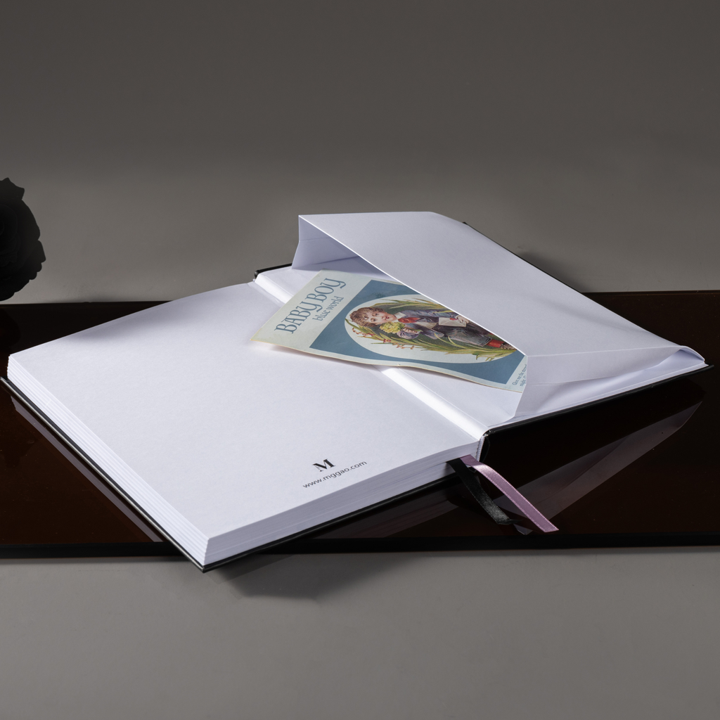 Inner back pocket of the Dream Garden iris notebook holding a color illustrated card, with a pink ribbon bookmark visible, styled on a dark surface.