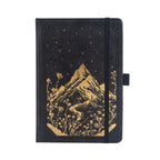 A5 black vegan leather notebook with gold foil mountain and starry night embossing, standing upright on a white background with a matching black elastic band.