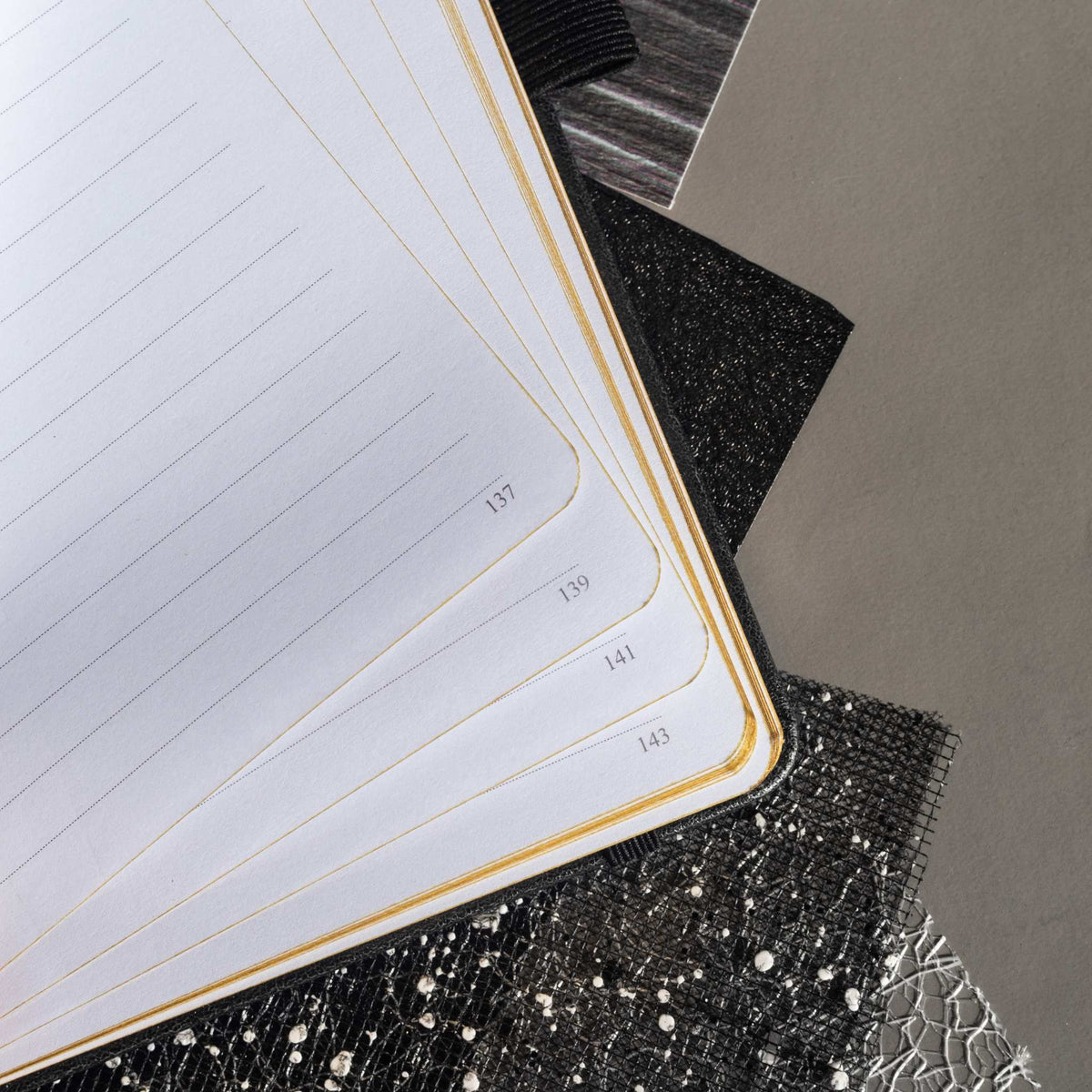 Close-up of the open A5 notebook showing the 100gsm lined paper interior with golden borders and corner. 