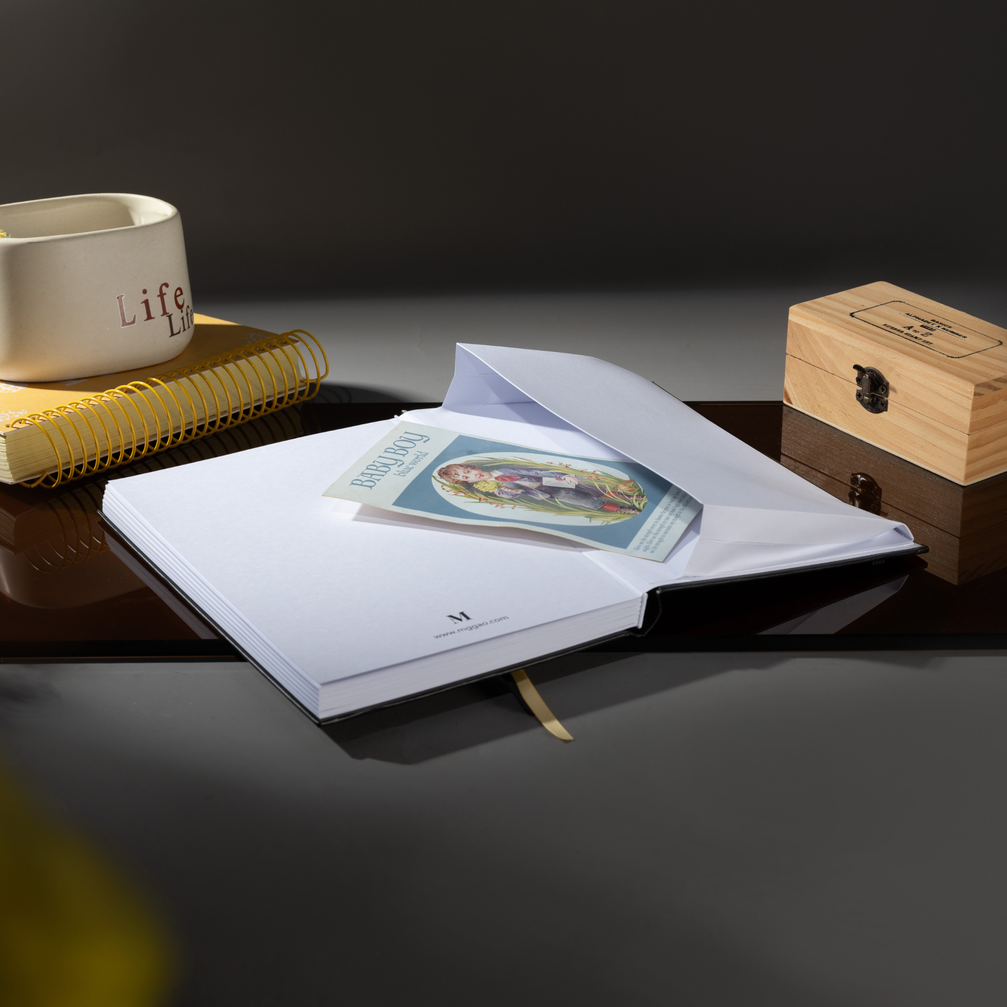 Inner back pocket of the Dream Garden sunflower notebook holding a color illustrated card, with a gold ribbon bookmark visible, styled on a dark reflective surface.
