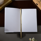 Open A5 lined notebook showing clean white pages with Date and Memo No. headers, a gold ribbon bookmark, and a black elastic closure.