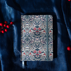 Flat lay of the blue floral fabric notebook on a dark blue cloth surface with scattered red berries.