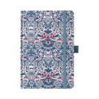 A5 blue ornamental floral fabric notebook standing upright on a white background with a matching blue elastic closure, featuring an intricate symmetrical botanical pattern with red and white accents.