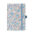 A5 lilac and blue ditsy floral fabric notebook standing upright on a white background, featuring a dense pattern of small pastel purple, blue, and peach blossoms, finished with a matching muted blue elastic closure.