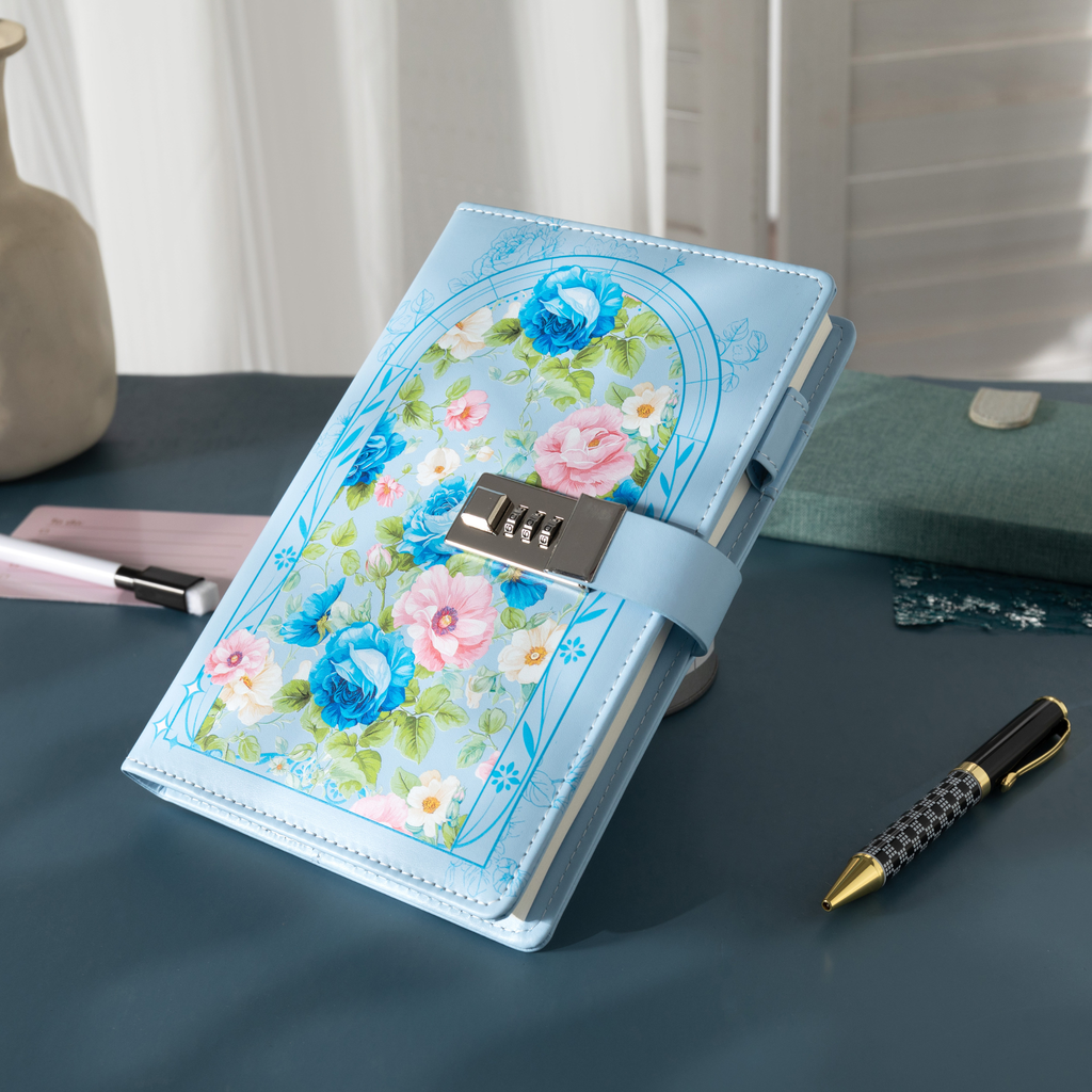Angled view of the light blue vegan leather notebook with a metal combination lock, showcasing the floral arch design with pink and blue blooms, gold gilded edges, and a matching blue elastic strap.