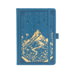 A5 deep blue vegan leather notebook with gold foil mountain and starry night embossing, standing upright on a white background with a matching blue elastic band.