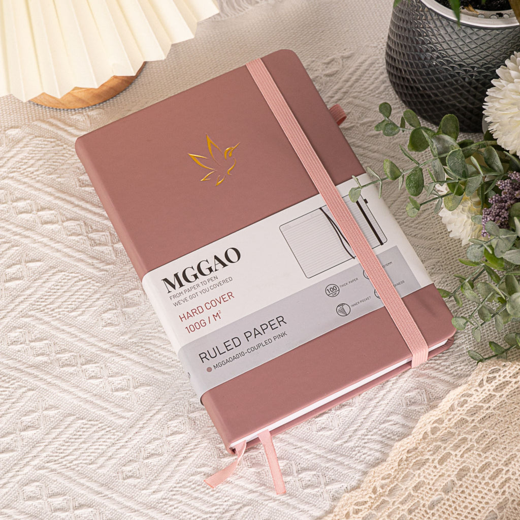 MGGAO A5 Couple Pink Vegan Leather Hummingbird Notebook with Packaging Sleeve on Textured Fabric with Plants