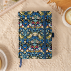Flat lay of the blue bird and floral fabric notebook on a cream textured blanket, surrounded by soft natural decor.
