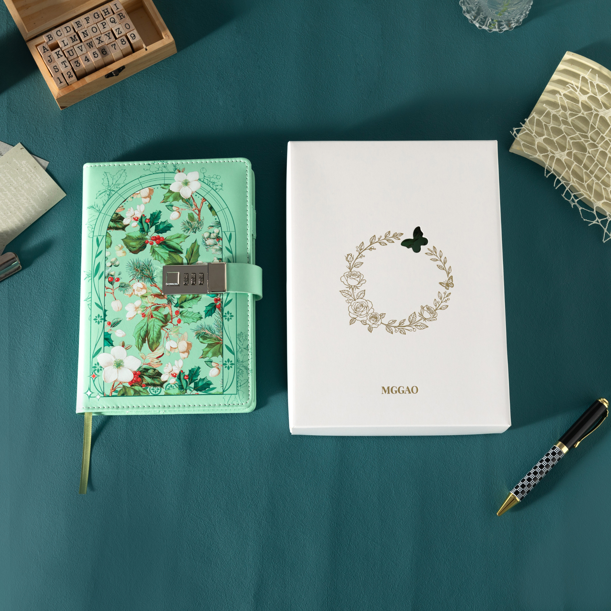 Green floral vegan leather notebook with lock placed next to its white gift box with a gold foil wreath logo.