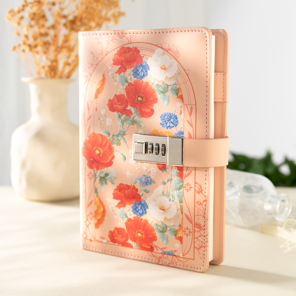 A5 orange vegan leather notebook with a 3-digit metal combination lock, featuring a colorful floral arch design, standing upright on a light desk with a dried flower vase in the background.