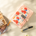 Top-down view of the orange vegan leather notebook laid flat, featuring a vibrant floral arch design, a 3-digit metal combination lock, and an orange ribbon bookmark, styled with wooden alphabet stamps and a patterned pen.