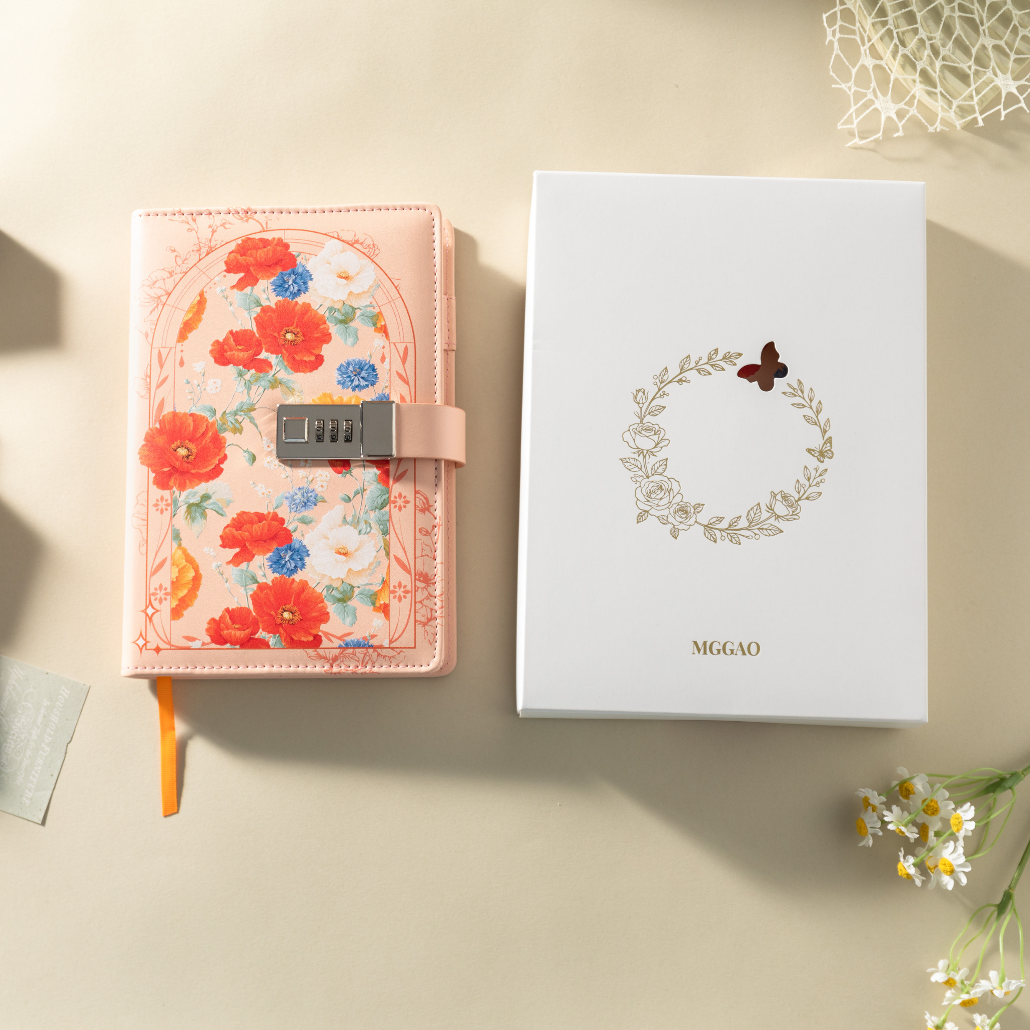 Orange floral vegan leather notebook with lock placed next to its white gift box with a gold foil wreath logo.