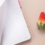 Close-up of a page being turned in the pink ditsy floral notebook, revealing the smooth lined paper interior and corner page number.