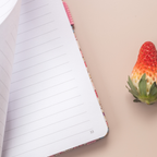 Close-up of a page being turned in the pink ditsy floral notebook, revealing the smooth lined paper interior and corner page number.