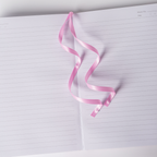 Pink satin ribbon bookmark elegantly resting on the open lined pages of the pink ditsy floral notebook.