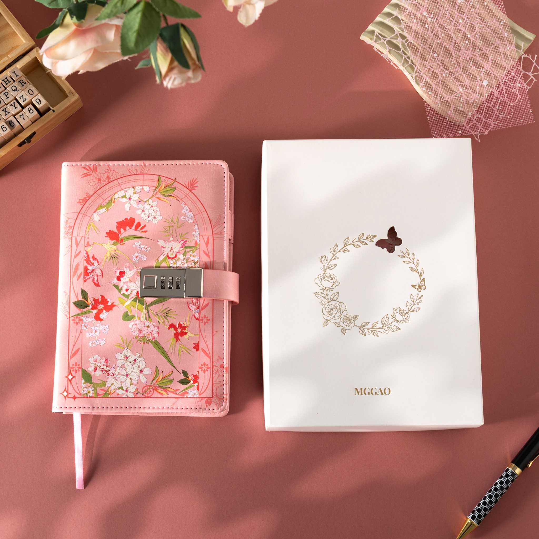 Pink floral vegan leather journal with lock placed next to its white gift box with a gold foil floral wreath logo.   