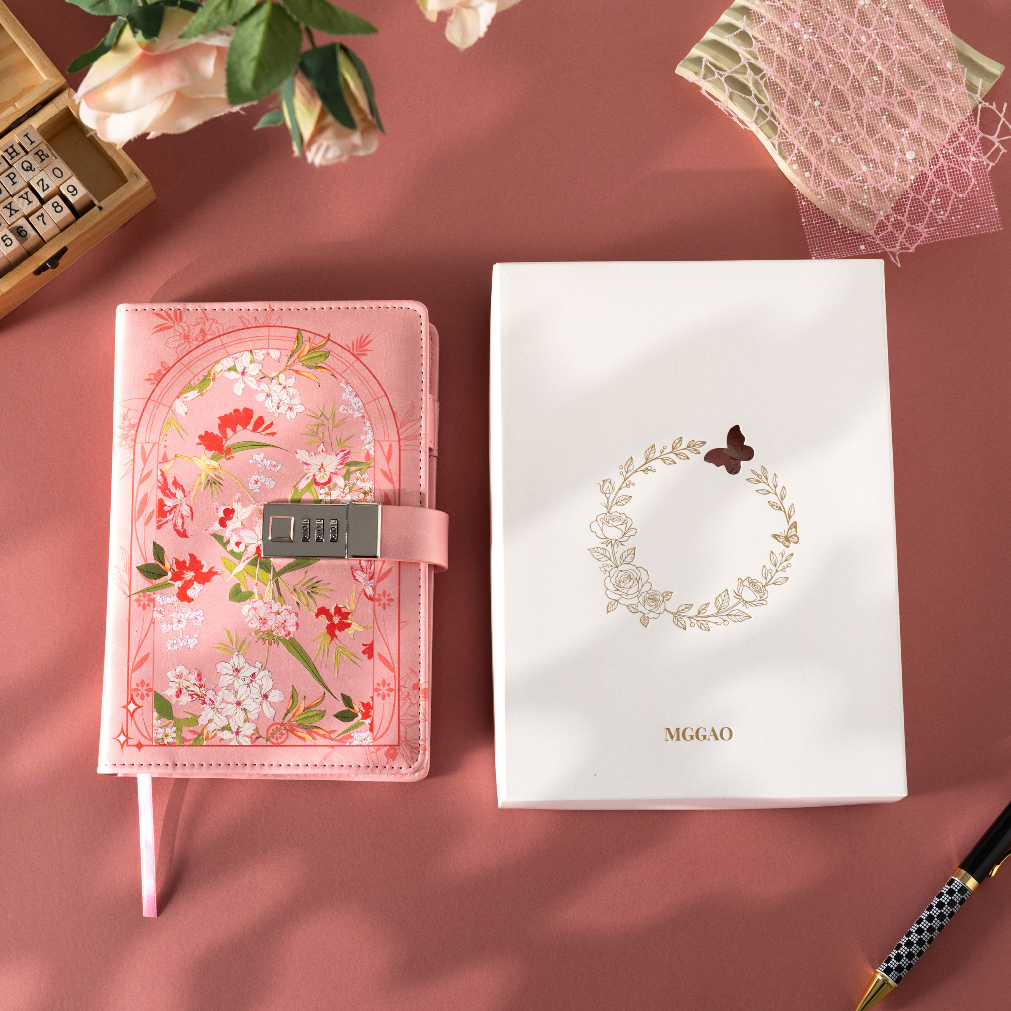 Pink floral vegan leather notebook with lock placed next to its white gift box with a gold foil floral wreath logo.   