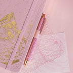 Detail of the gold foil mountain embossing on the pink vegan leather cover, paired with a matching pink glitter pen.