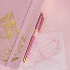 Detail of the gold foil mountain embossing on the pink vegan leather cover, paired with a matching pink glitter pen.