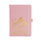 A5 pink vegan leather notebook with gold foil mountain and starry night embossing, standing upright on a white background with a matching pink elastic band.