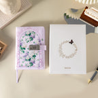 Purple floral vegan leather journal with lock placed next to its white gift box with a gold foil wreath logo.