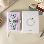 Purple floral vegan leather notebook with lock placed next to its white gift box with a gold foil wreath logo.