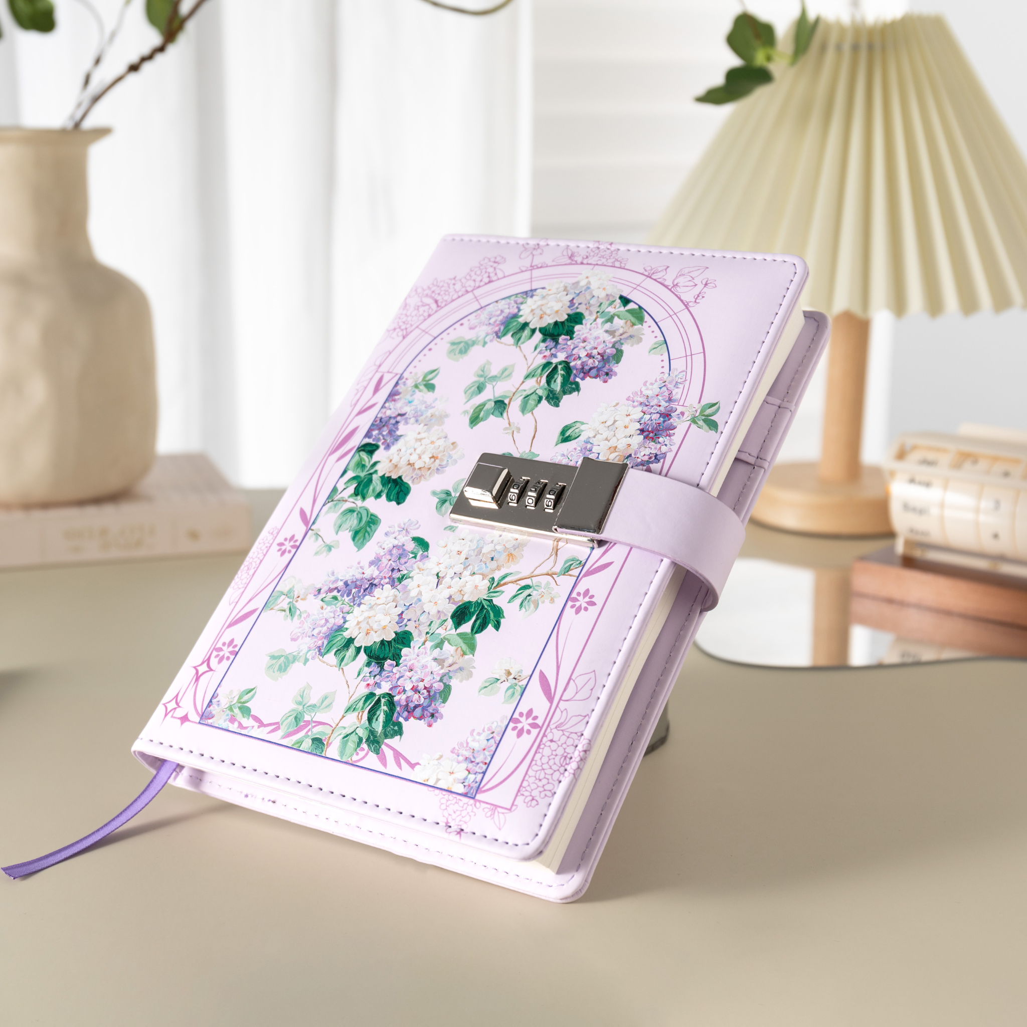 Angled view of the purple floral lockable notebook resting on a light beige surface, showcasing the botanical arch design and metal lock.