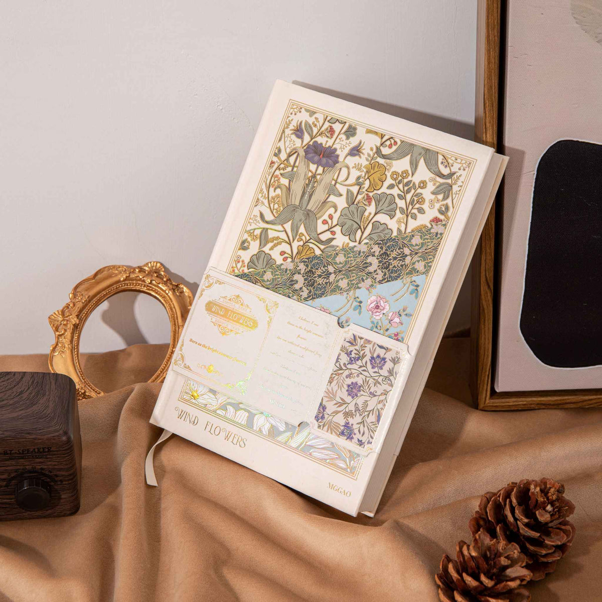 A5 Wind Flowers Hardcover Lined Notebook with Belly Band on Wooden Desk, Vintage Gold Frame and Pinecones