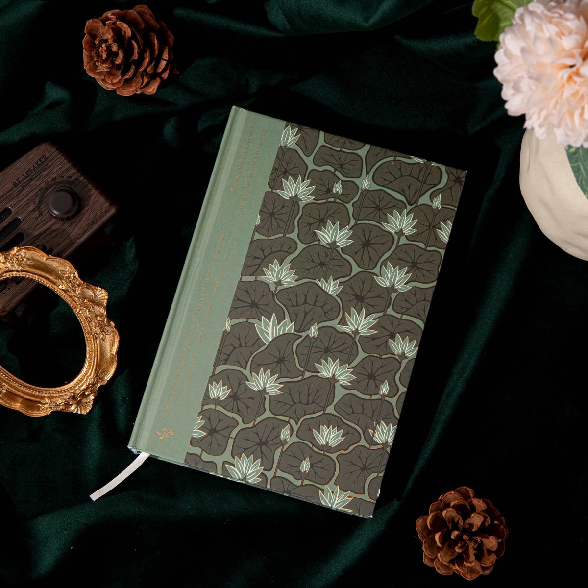 A5 Wind Flowers Hardcover Lined Notebook Side View on Dark Green Silk, Gold Foil Spine and Water Lily Cover Detail