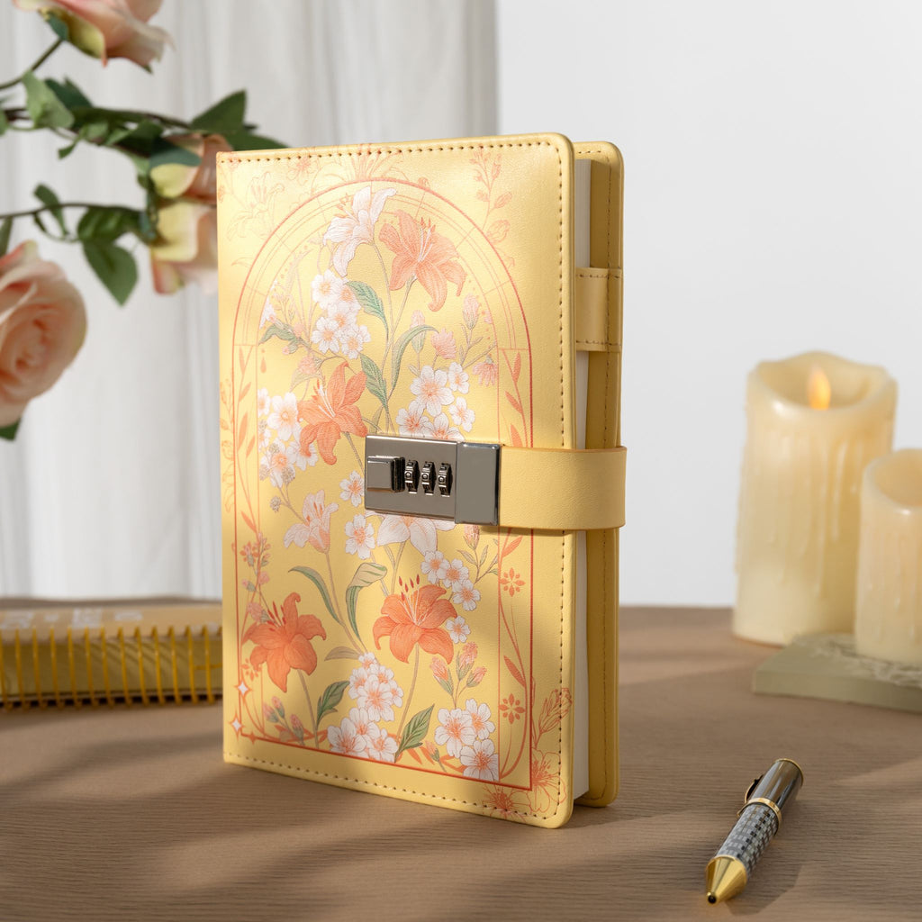 A5 yellow floral vegan leather journal standing upright on a light wooden desk, featuring a metal combination lock, yellow elastic band, and styled with a candle and flowers.