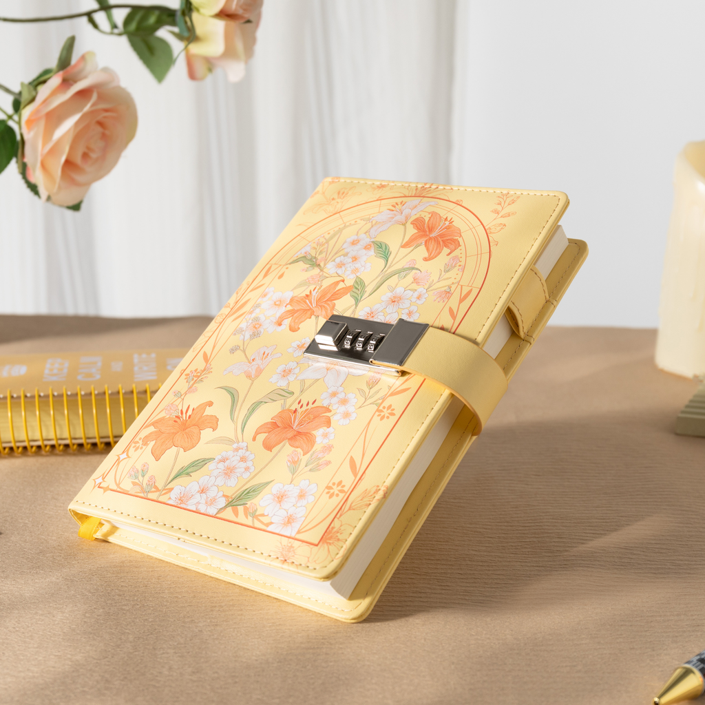 Angled view of the sunny yellow floral lockable journal resting on a wooden desk, showcasing the metal lock strap, gold gilded page edges, and a matching yellow ribbon.