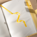 Close-up of the open lined paper interior with a yellow satin ribbon bookmark resting on the page.