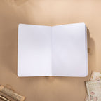 Open A5 journal laid flat on a wooden surface, displaying the clean 160gsm dot grid paper interior with a beige ribbon bookmark.