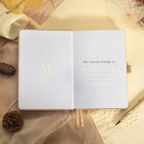 Inside front page of the beige mountain journal featuring a gold foil "M" logo and "This Journal Belongs To" ownership section.