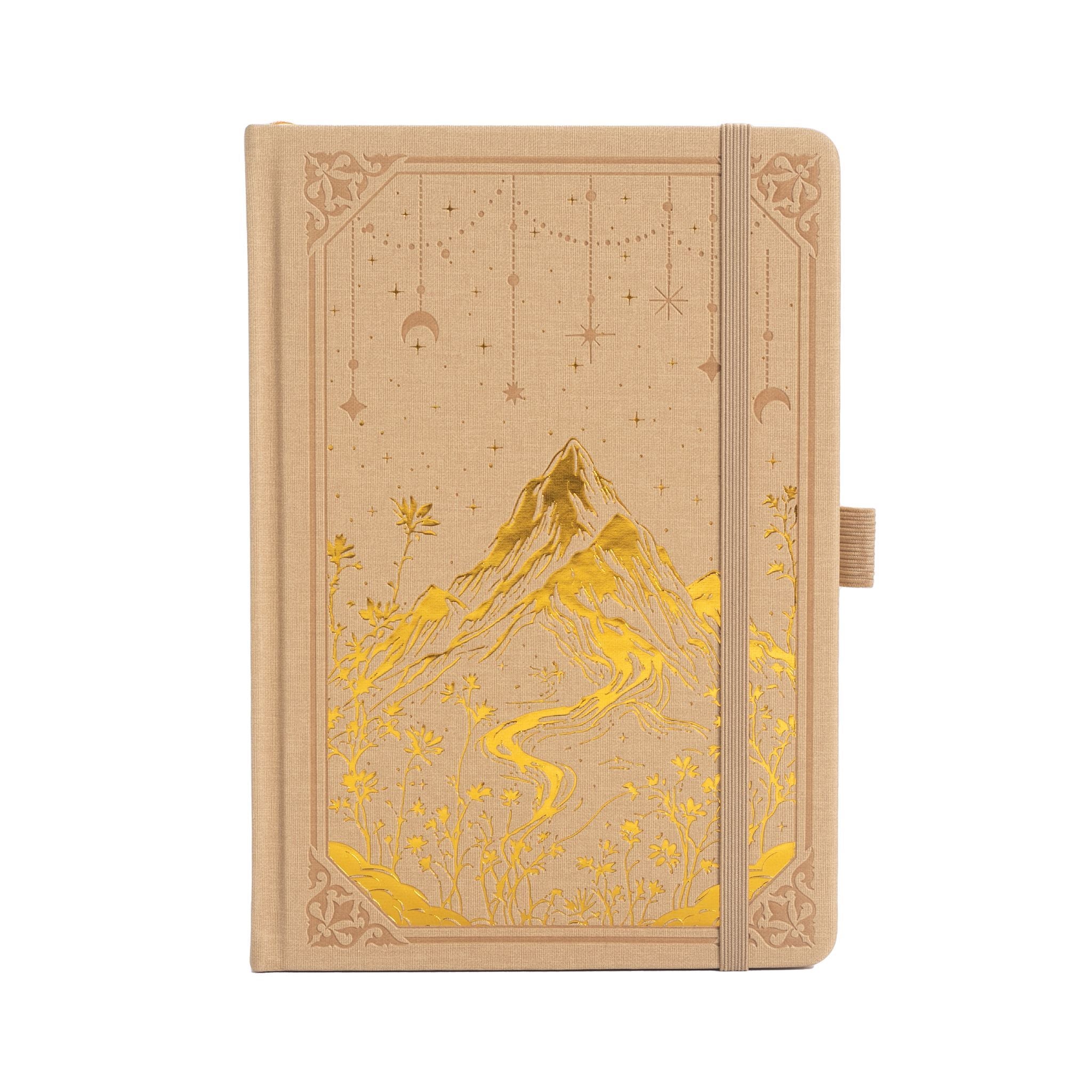 A5 beige vegan leather notebook with gold foil mountain and starry night embossing, standing upright on a white background with a matching beige elastic band.