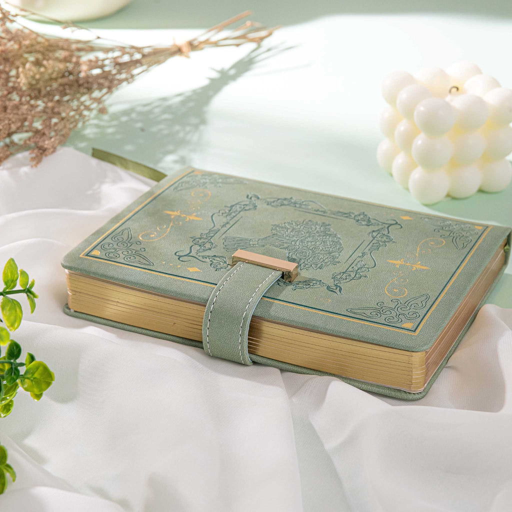 B6 Green Rose Embossed Vegan Leather Journal with Gold Heart Lock and Gilded Edges, Lying on White Fabric with Decorations