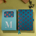 Teal-blue embroidered scalloped fabric notebook displayed next to its signature light blue window-cut gift box