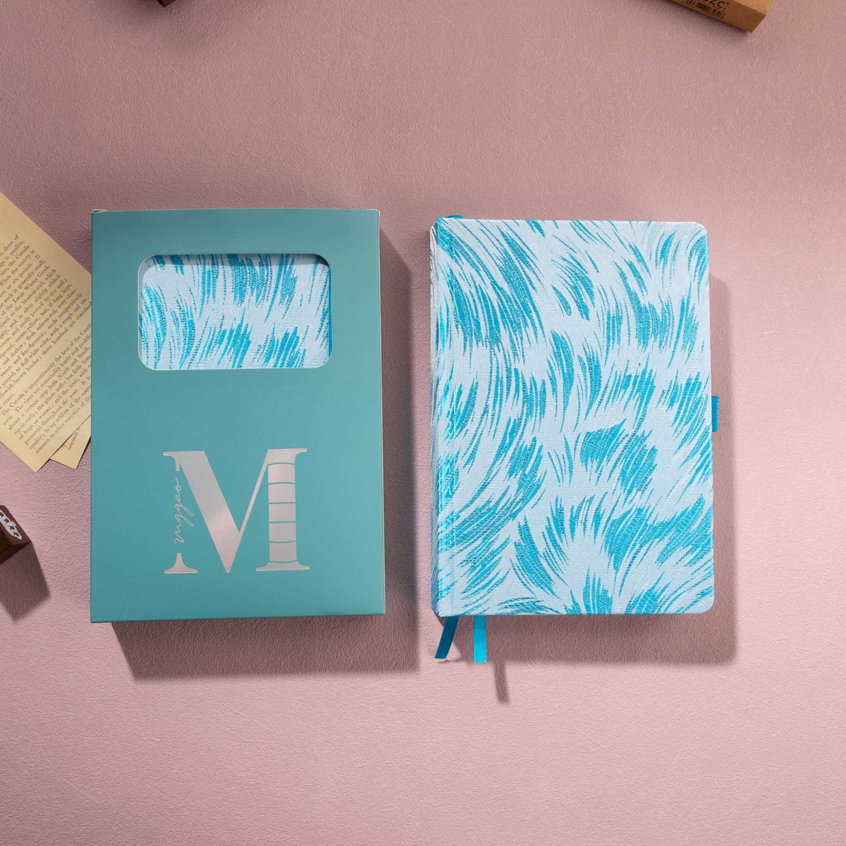 Light blue embroidered feather fabric notebook displayed next to its signature light blue window-cut gift box