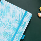 Close-up of the raised light blue embroidery on a white woven fabric cover, with elastic strap