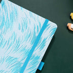 Close-up of the raised light blue embroidery on a white woven fabric cover, with elastic strap