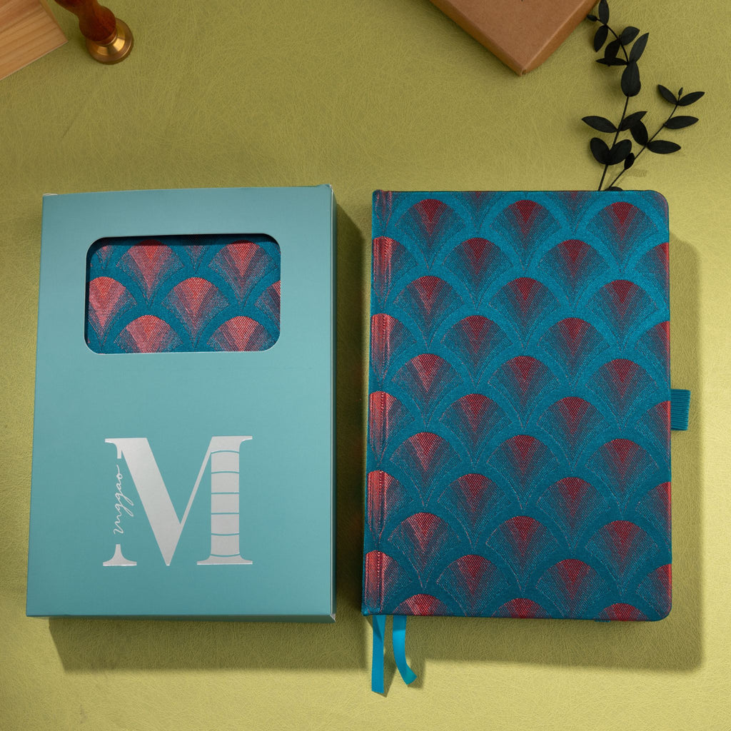Teal-blue embroidered scalloped fabric notebook displayed next to its signature light blue window-cut gift box