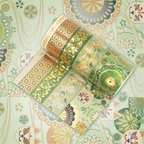 Green and gold brocade washi tape rolls displayed flat, showcasing delicate floral patterns and gold foil accents on a matching patterned background.