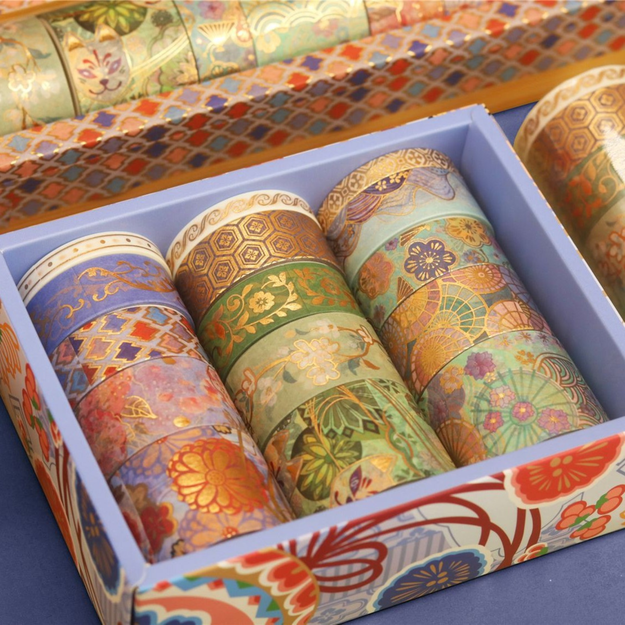 Top-down view of the light blue decorative box containing multiple rows of green and purple gold foil washi tape rolls, neatly organized in a beautiful storage box.