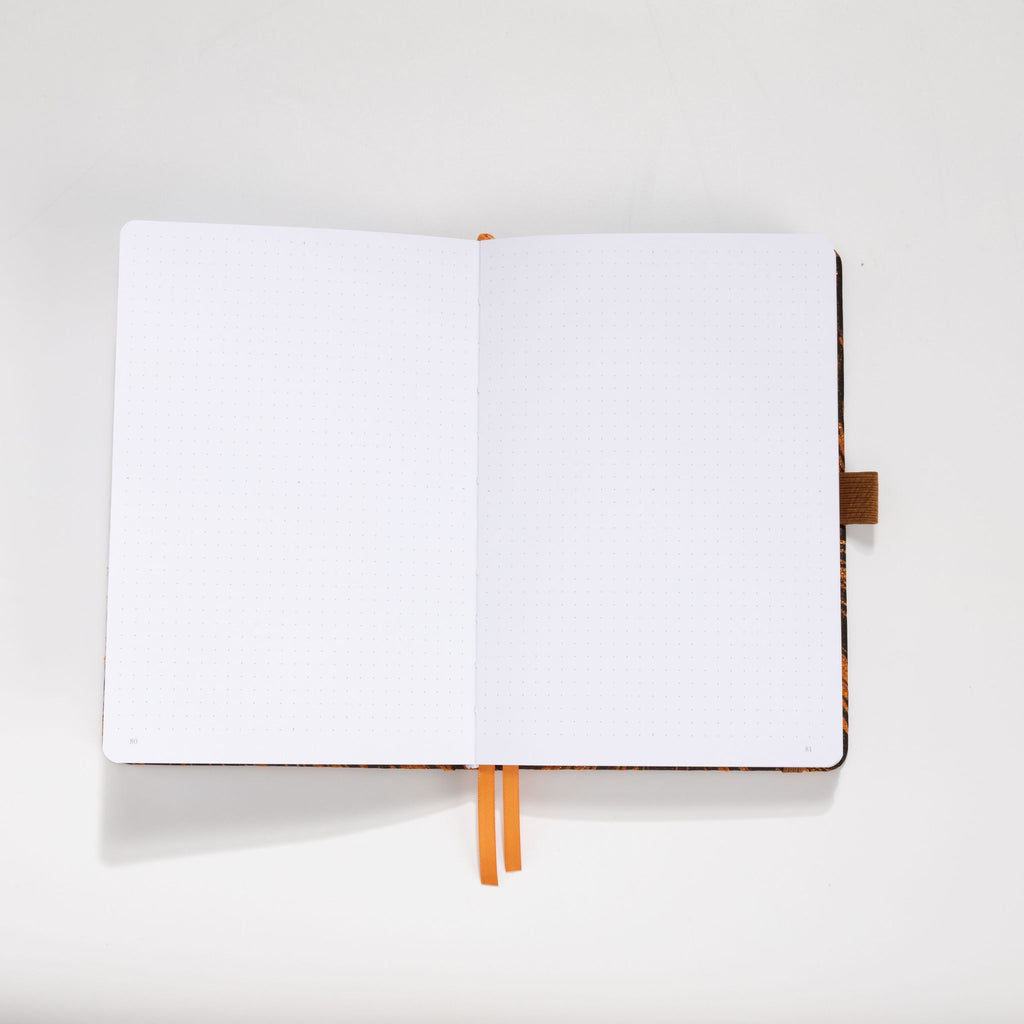 Open A5 journal showing the 160gsm dot grid interior pages with orange ribbon bookmark