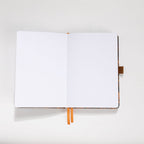 Open A5 journal showing the 160gsm dot grid interior pages with orange ribbon bookmark