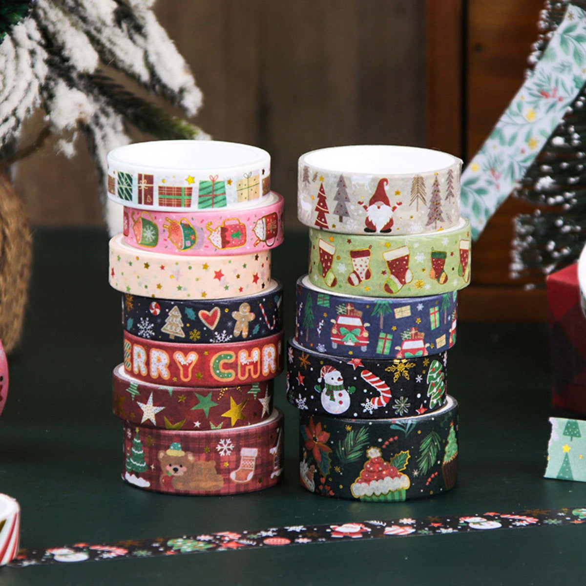 Christmas Gold Foil Washi Tape Set 12 Rolls, Stacked Rolls on Dark Green Table with Christmas Tree Background