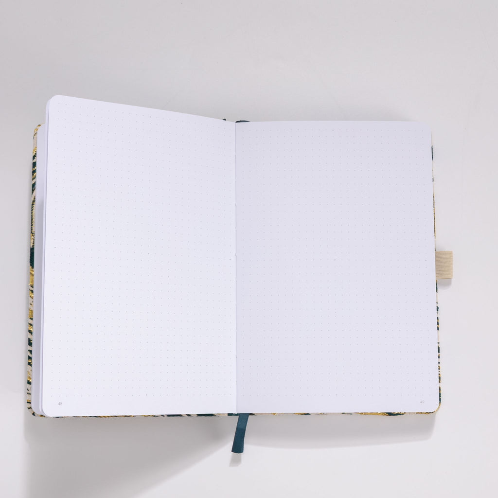 Open A5 journal showing the 160gsm dot grid interior pages with dark blue ribbon bookmark