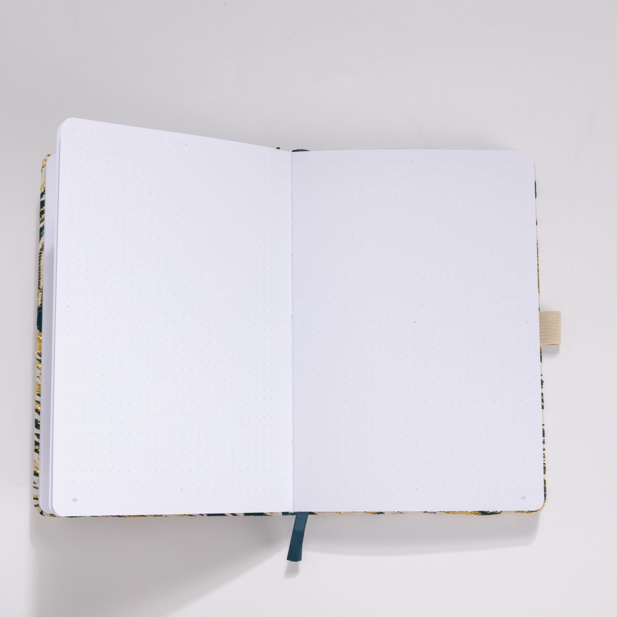 Open A5 journal showing the 160gsm dot grid interior pages with dark blue ribbon bookmark